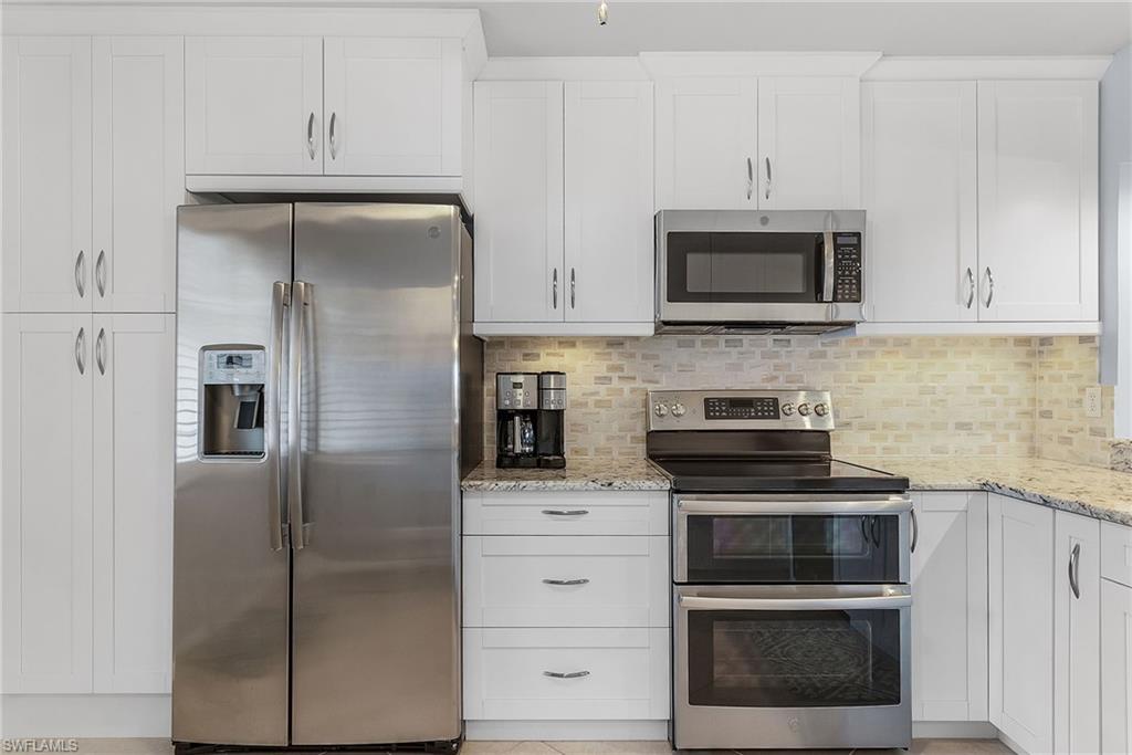 6780 Dennis Circle, Unit M206 Naples, FL 34104 - Photo 4 of 26 a kitchen with stainless steel appliances white cabinets and a refrigerator