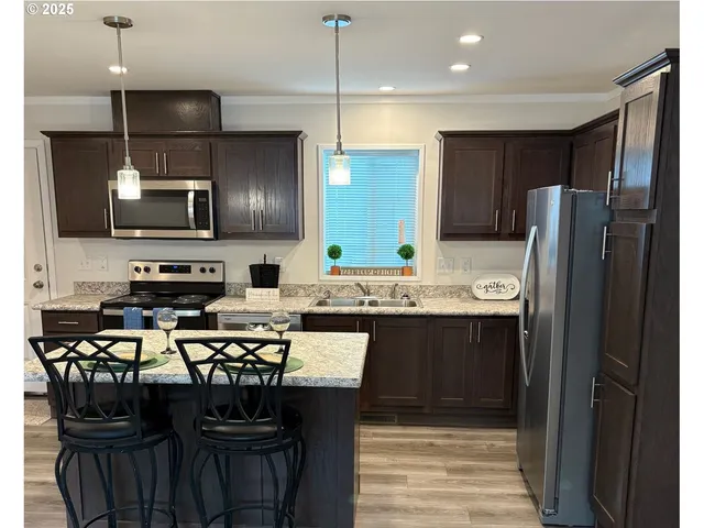 a kitchen with stainless steel appliances granite countertop a refrigerator stove a sink and a microwave