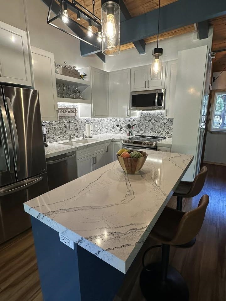 3252 Chateau Road, Unit 43 Mammoth Lakes, CA 93546 - Photo 3 of 29 White shaker cabinetry, patterned tile backsplash, stainless steel appliances, and a kitchen island with stone countertop
