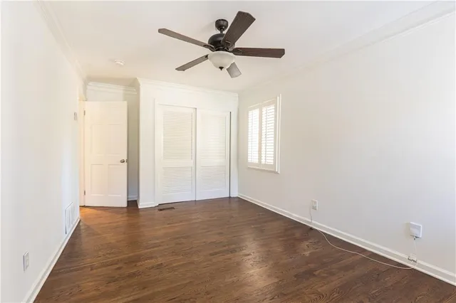 an empty room with wooden floor ceiling fan and windows