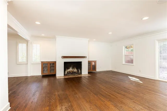 an empty room with wooden floor fireplace and windows