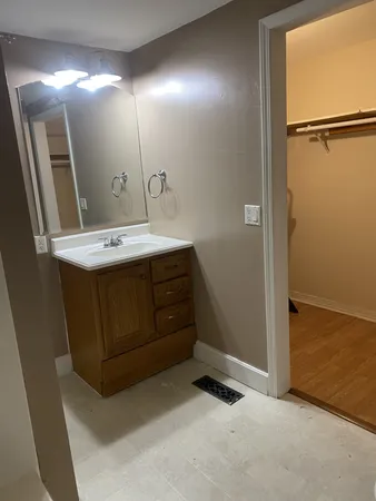 an empty room with wooden floor cabinet and mirror