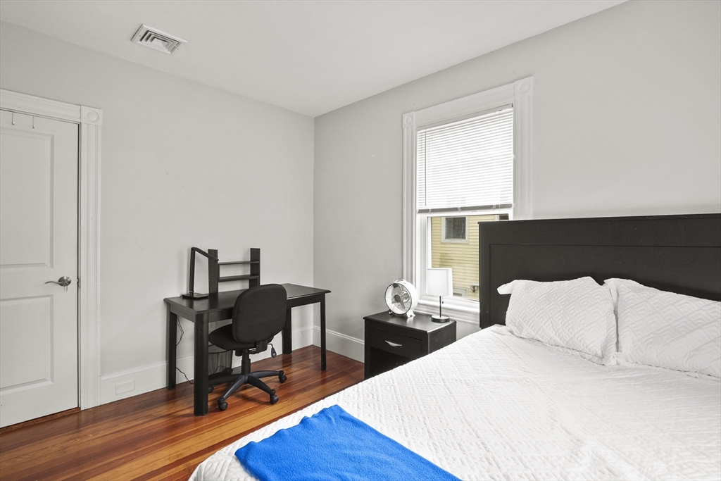 139 Adams Street, Unit 3 Waltham, MA 02453 - Photo 13 of 17 a bedroom with a bed a desk and chair with wooden floor