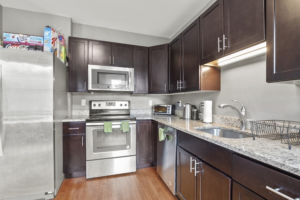 139 Adams Street, Unit 3 Waltham, MA 02453 - Photo 4 of 17 a kitchen with stainless steel appliances granite countertop a refrigerator stove and sink