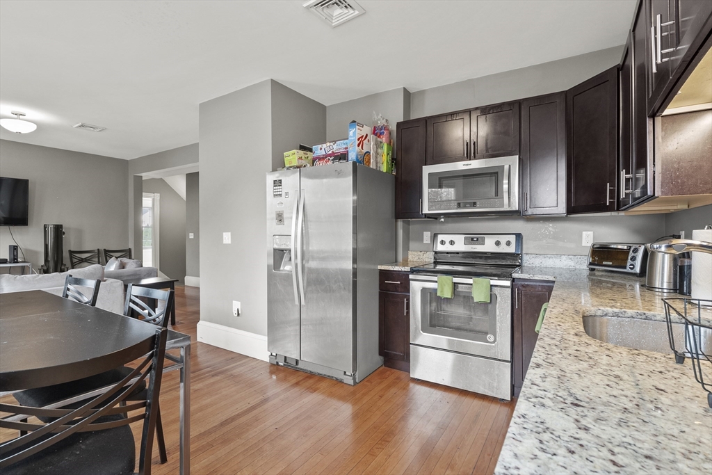 139 Adams Street, Unit 3 Waltham, MA 02453 - Photo 5 of 17 a kitchen with stainless steel appliances wooden floor and a refrigerator