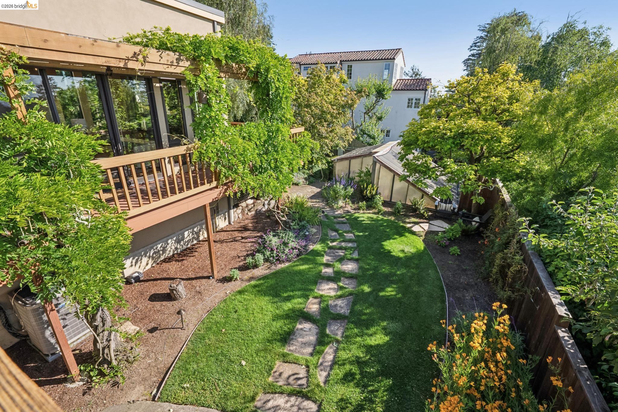 576 Vistamont Avenue Berkeley, CA 94708 - Photo 25 of 33 Expansive backyard featuring a manicured lawn, stone pathway, and mature landscaping
