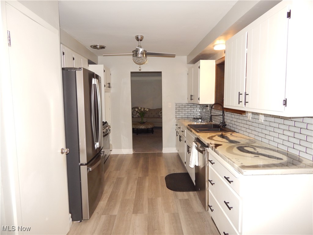 2128 Miami Road Euclid, OH 44117 - Photo 12 of 36 Kitchen with stainless steel appliances, sink, white cabinets, and light hardwood / wood-style floors