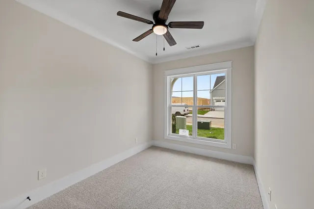 an empty room with windows and ceiling fan