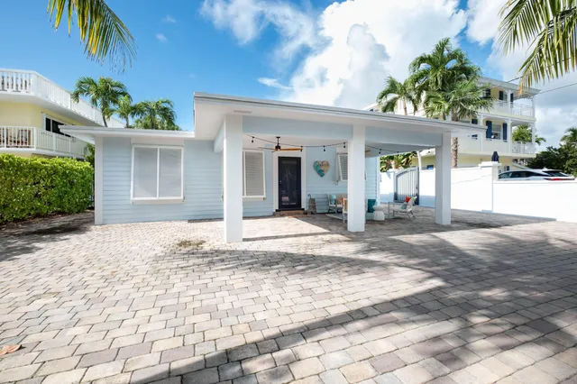 a view of a house with a yard and palm trees