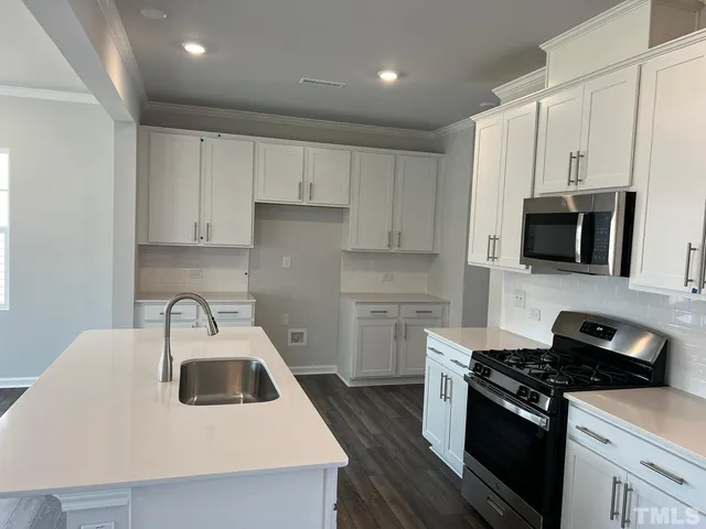 a kitchen with stainless steel appliances a white stove top oven a sink a refrigerator and white cabinets