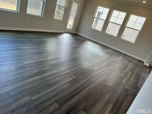 a view of an empty room with wooden floor and windows