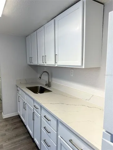 a kitchen with granite countertop white cabinets and sink
