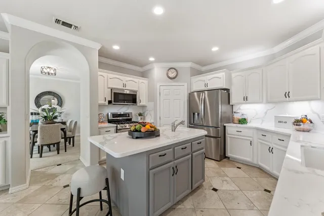 a kitchen with a sink white cabinets and stainless steel appliances