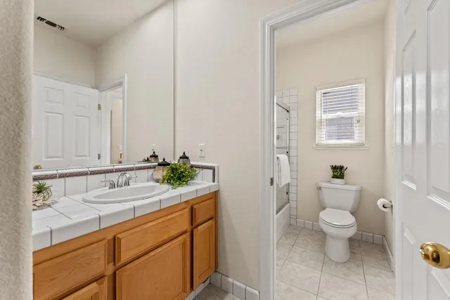 a bathroom with a granite countertop sink a toilet and a mirror