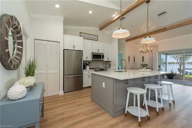 a kitchen with stainless steel appliances granite countertop a refrigerator a sink dishwasher a stove and a dining table with wooden floor