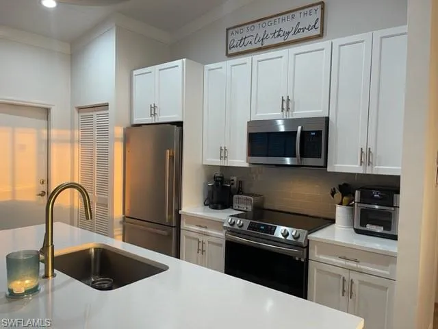 a kitchen with white cabinets and stainless steel appliances
