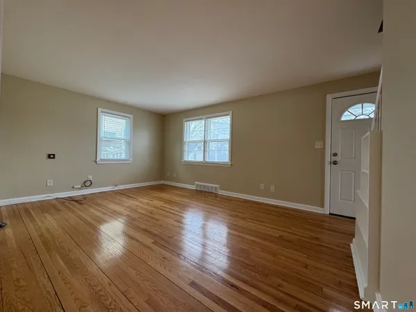 an empty room with wooden floor and windows