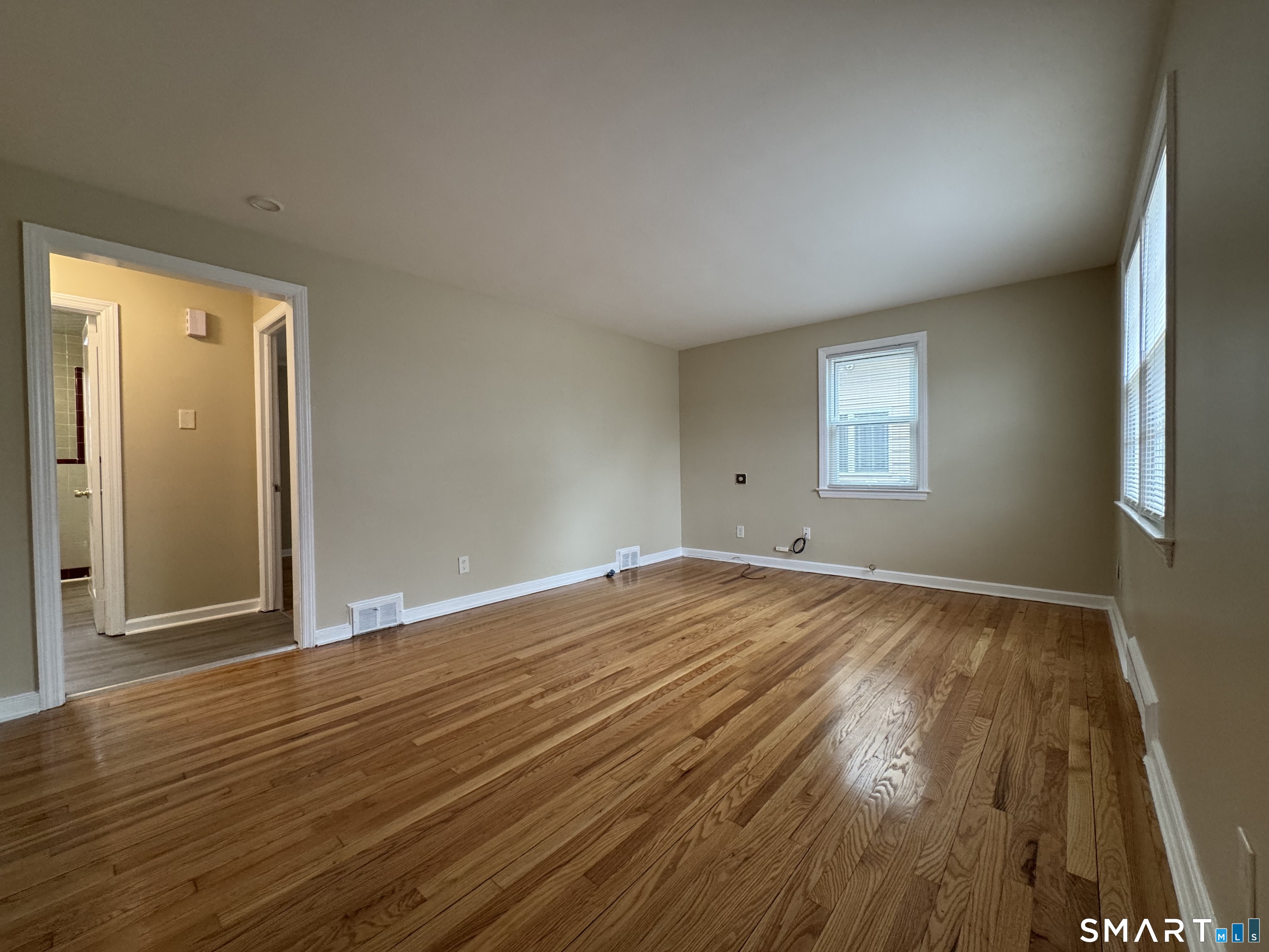 56 Sidney Street Bridgeport, CT 06606 - Photo 4 of 12 a view of empty room with wooden floor and fan