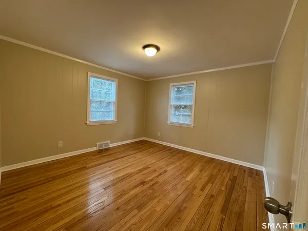 a view of an empty room with wooden floor and a window