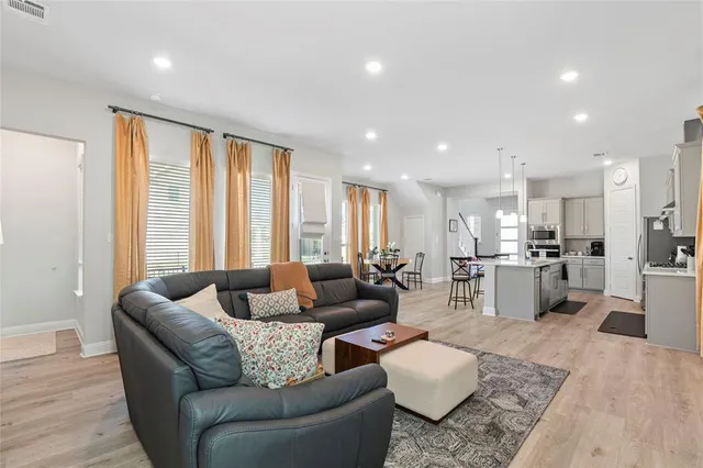 a living room with stainless steel appliances furniture windows and a flat screen tv