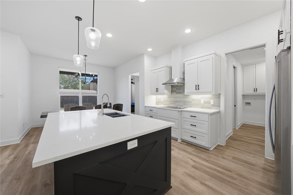 314 James Street Mabank, TX 75147 - Photo 16 of 25 a large kitchen with kitchen island a stove a sink dishwasher and a refrigerator with wooden floor