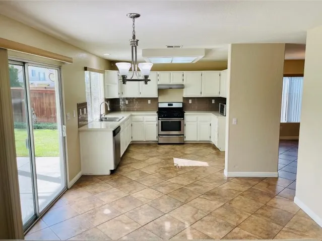 a kitchen with stainless steel appliances a white stove top oven cabinets a sink and a counter space