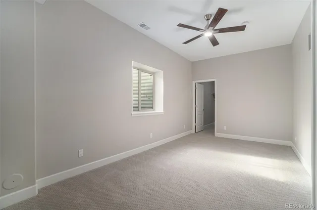 an empty room with a ceiling fan and windows