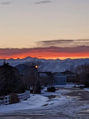 a view of a backyard with lawn chairs under an umbrella