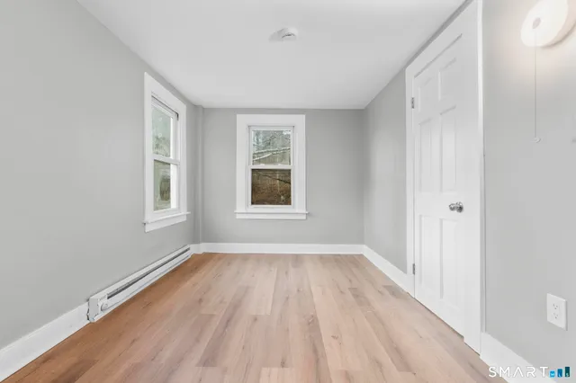 a view of an empty room with wooden floor and a window