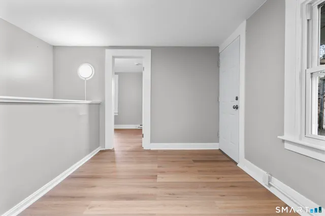 a view of an empty room with wooden floor and a window