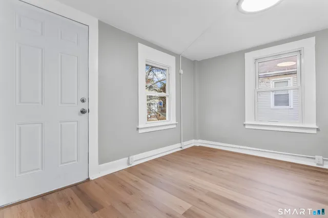 a view of an empty room with wooden floor and a window