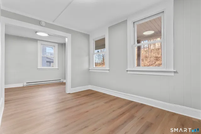 a view of an empty room with wooden floor and a window