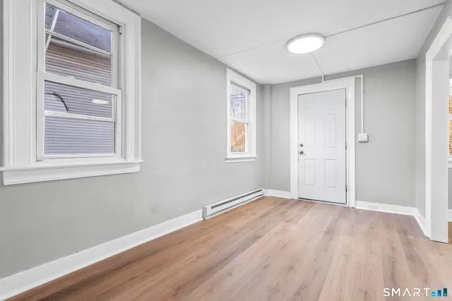 a view of an empty room with wooden floor and a window
