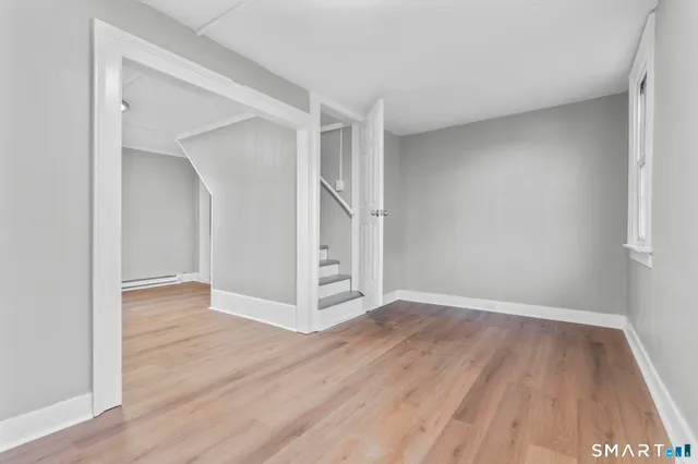 a view of an empty room with wooden floor and closet