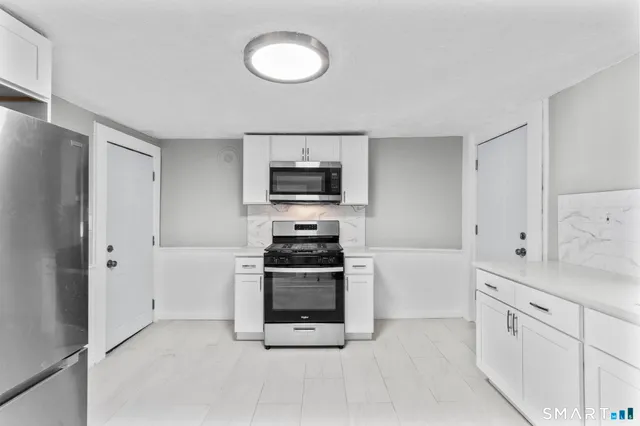 a view of kitchen with refrigerator and white cabinets