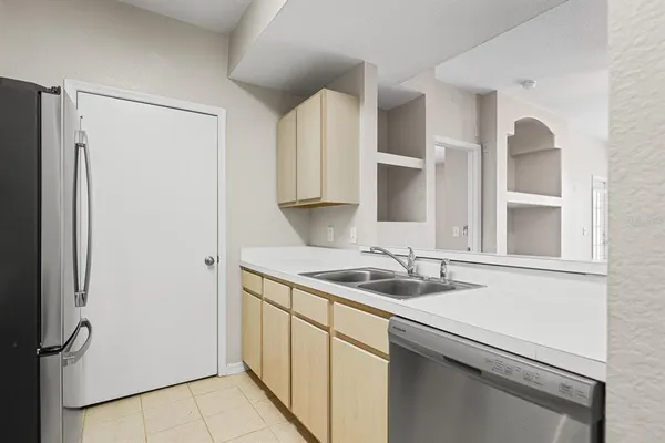 a kitchen with stainless steel appliances granite countertop a sink and a refrigerator with wooden cabinets