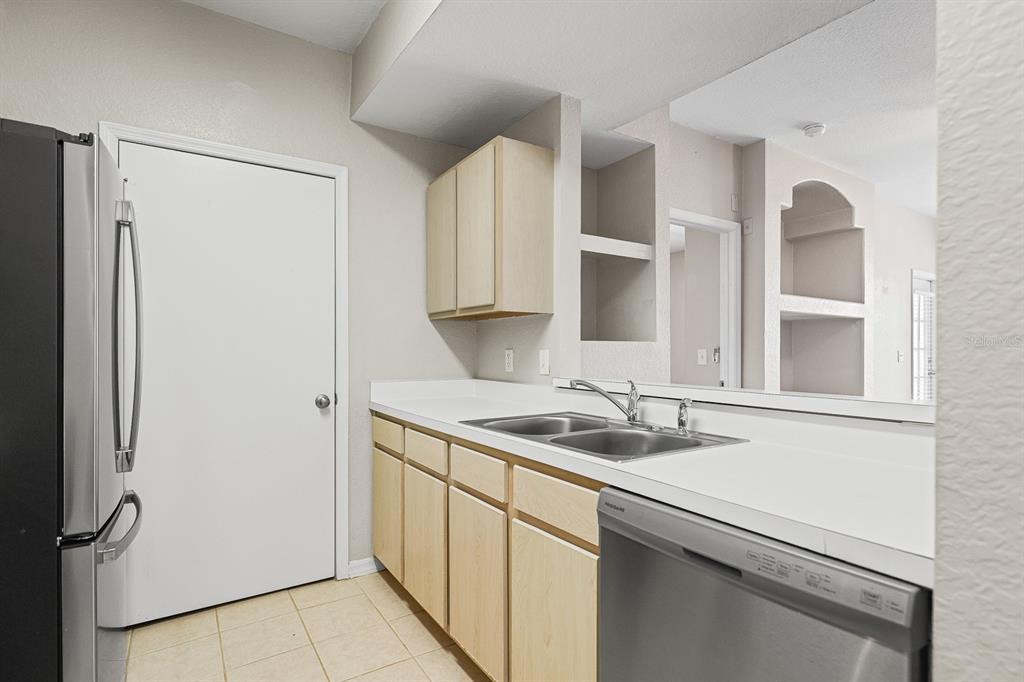 8513 Lucuya Way, Unit 209 Temple Terrace, FL 33637 - Photo 12 of 21 a kitchen with stainless steel appliances granite countertop a sink and a refrigerator with wooden cabinets