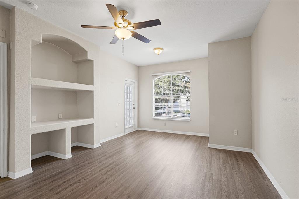 8513 Lucuya Way, Unit 209 Temple Terrace, FL 33637 - Photo 6 of 21 an empty room with wooden floor chandelier fan and windows