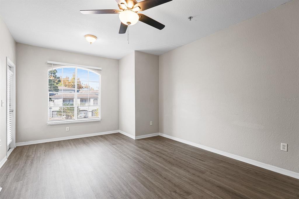 8513 Lucuya Way, Unit 209 Temple Terrace, FL 33637 - Photo 7 of 21 an empty room with wooden floor chandelier fan and windows