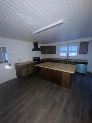 a kitchen with stainless steel appliances wooden cabinets granite counter tops and a wooden floor