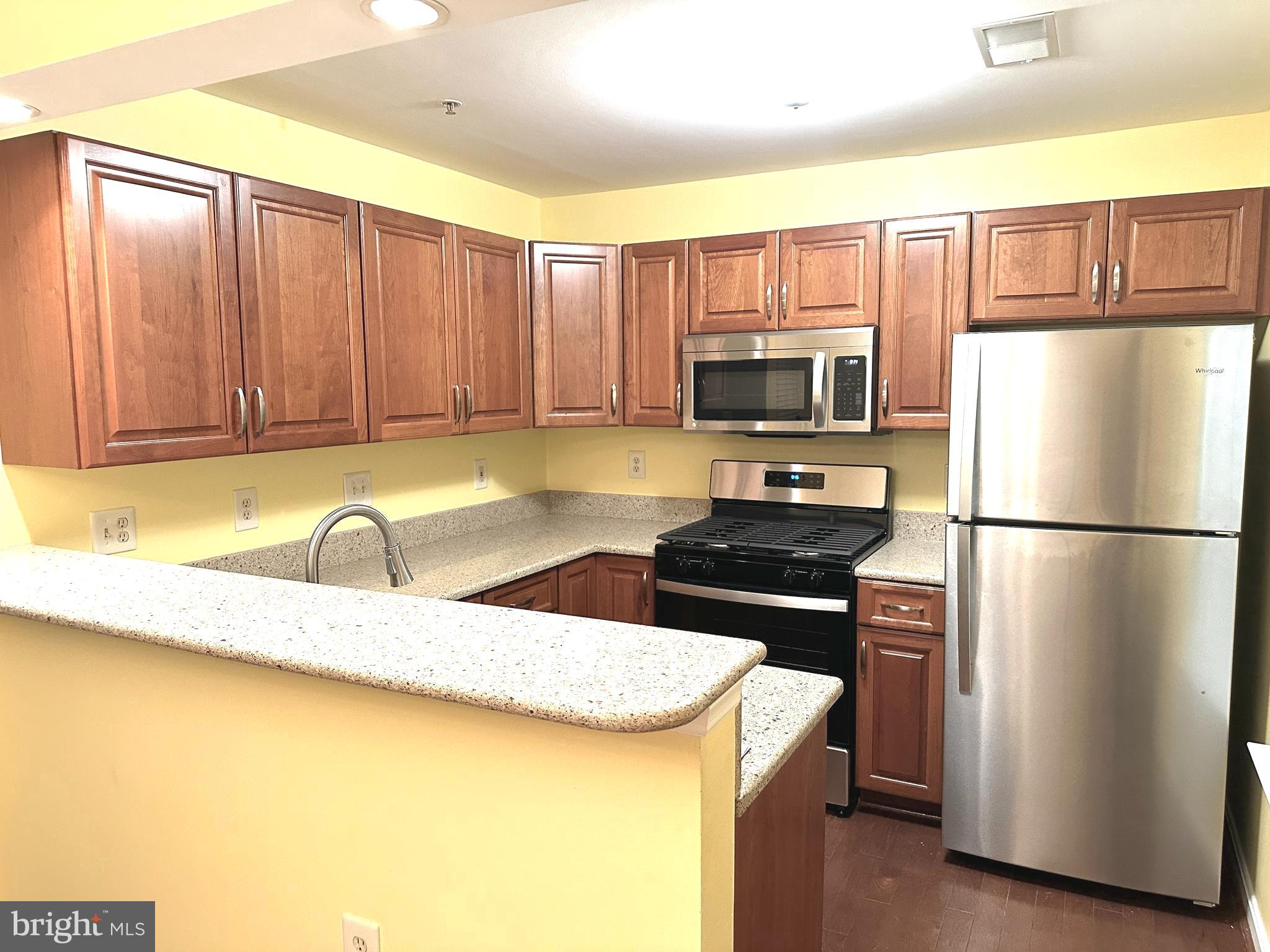 115 Timberbrook Lane, Unit 102 Gaithersburg, MD 20878 - Photo 6 of 20 a kitchen with granite countertop a refrigerator a stove a sink a counter space and cabinets