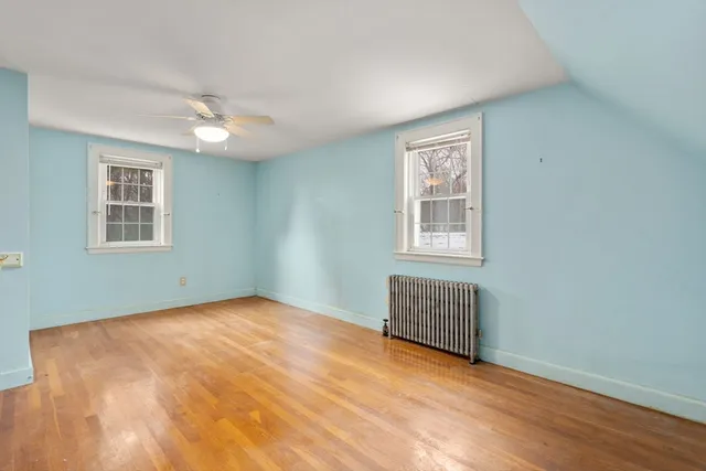 a view of an empty room with a window and wooden floor