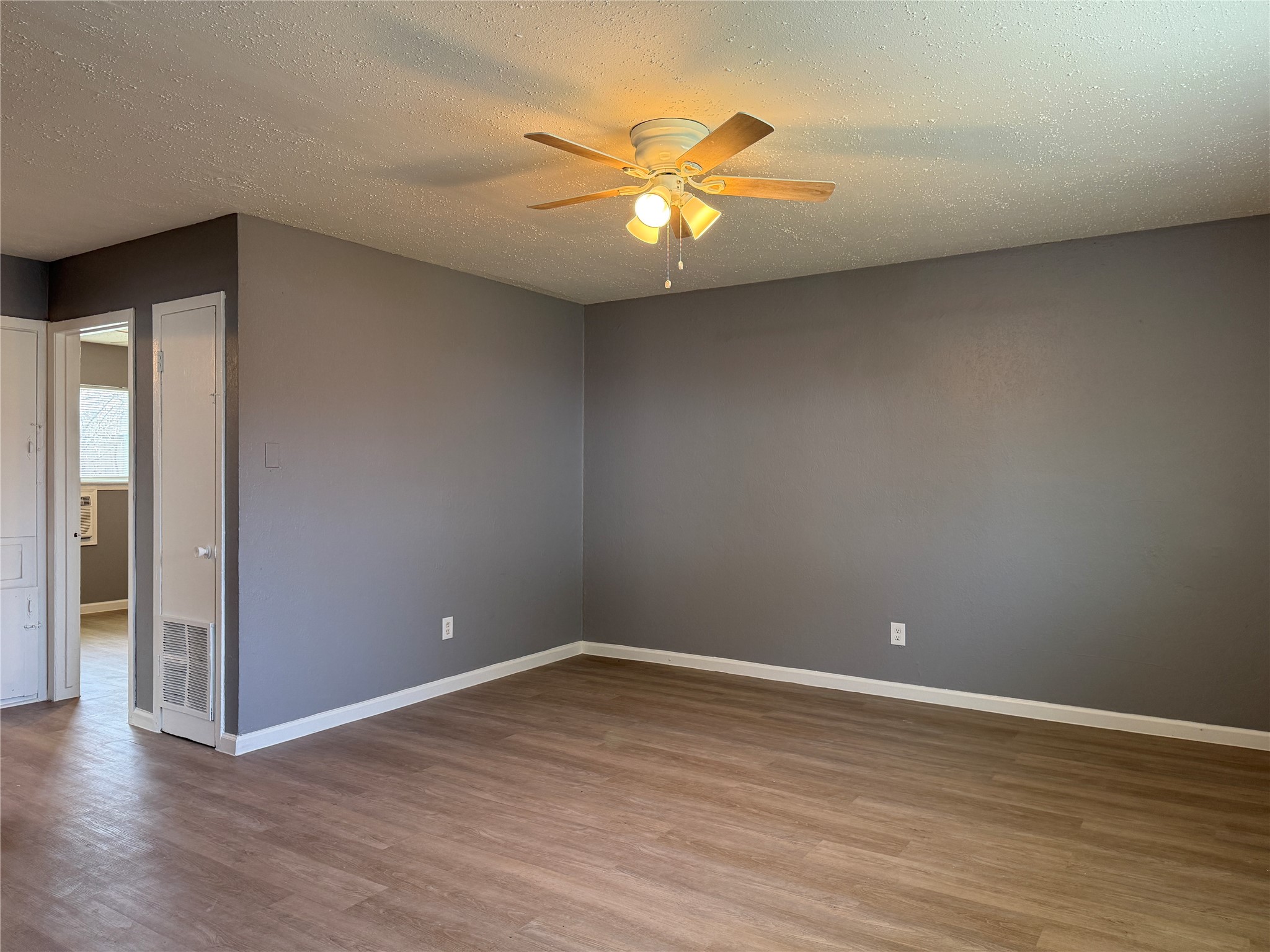 8010 Roswell Street, Unit 3 Houston, TX 77022 - Photo 4 of 12 a view of an empty room with wooden floor and a ceiling fan