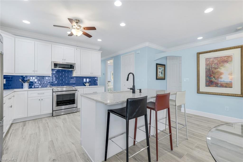 746 101st Avenue North Naples, FL 34108 - Photo 6 of 33 a kitchen with stainless steel appliances kitchen island granite countertop a stove a sink a dining table and chairs