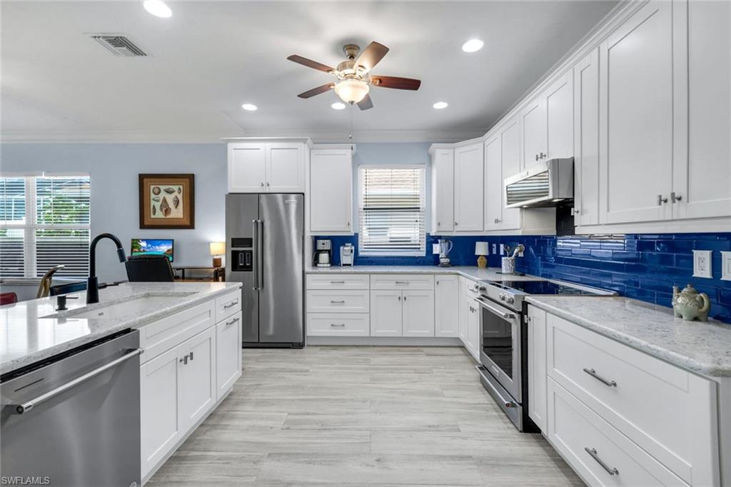 746 101st Avenue North Naples, FL 34108 - Photo 8 of 33 a kitchen with white cabinets and stainless steel appliances