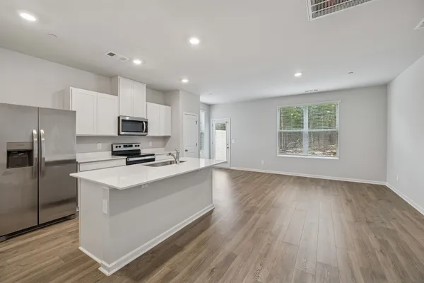 a kitchen with stainless steel appliances a sink a stove a refrigerator cabinets and a window