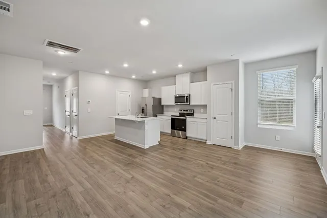 a view of kitchen with kitchen island wooden floor refrigerator and white cabinets