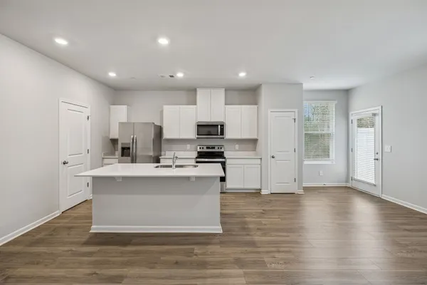 a view of kitchen with stainless steel appliances granite countertop a stove top oven a sink and a refrigerator