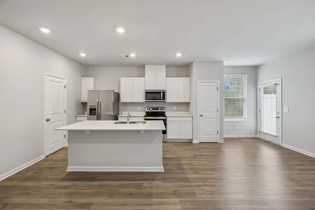 a view of kitchen with stainless steel appliances granite countertop a stove top oven a sink and a refrigerator
