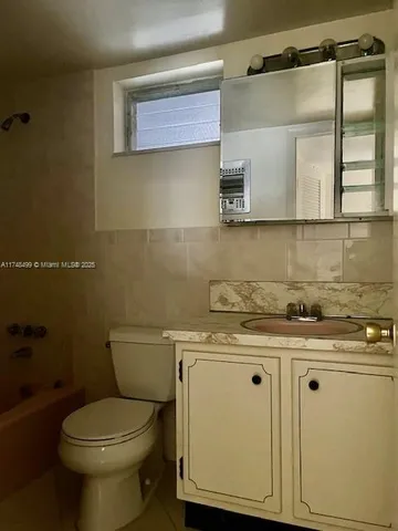 a bathroom with a granite countertop toilet sink and mirror